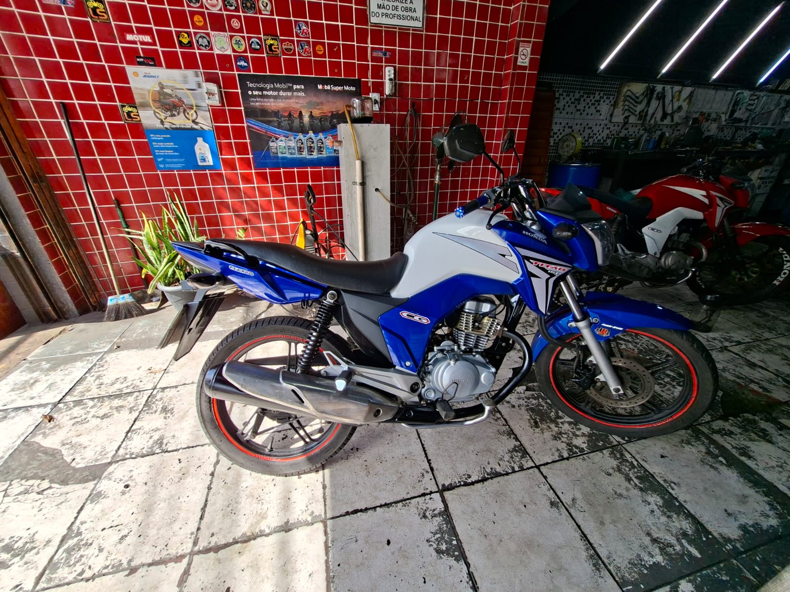 Honda CG Titan 150 azul montada e restaurada em frente à oficina